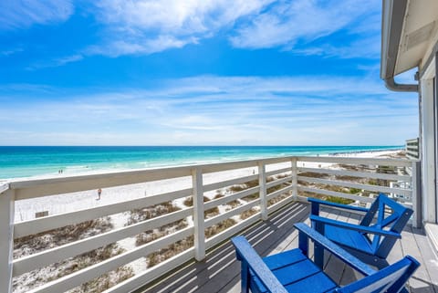 Stunning beachfront balcony with vibrant blue chairs overlooking pristine white sand and turquoise waters.