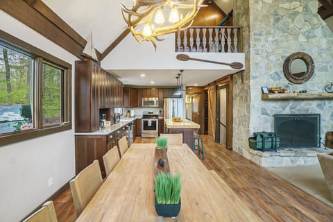 Enjoy meals surrounded by nature in the dining area, featuring a rustic antler chandelier and stunning woodland view