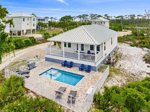 Elevated coastal retreat set among native pines, featuring a private pool with paver deck and spacious balcony overlooking the tranquil natural landscape.