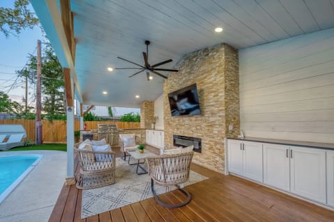 Luxury patio with TV, fireplace, outdoor kitchen, and poolside seating.