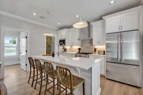 2nd Floor: Fully equipped kitchen stocked with all culinary essentials featuring stainless-steel appliances and a kitchen island offering ample counter space and bar seating.