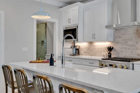 2nd Floor: Fully equipped kitchen stocked with all culinary essentials featuring stainless-steel appliances and a kitchen island offering ample counter space and bar seating.