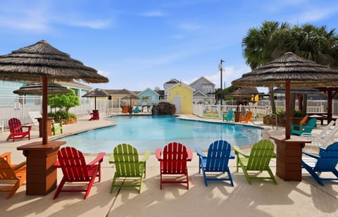 Resort Pool — Colorful Adirondack Chair Row, Tiki Umbrellas, Rock Waterfall & Cottages