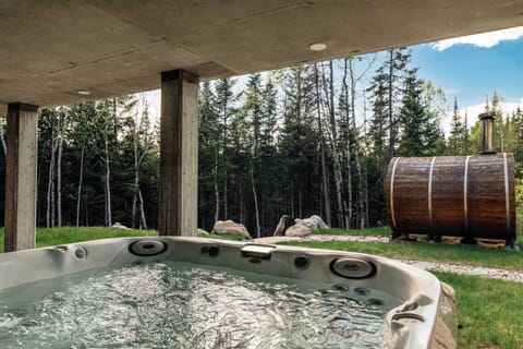 Depuis le spa, profitez d’une belle vue sur le sauna niché au cœur de la nature, avec un foyer extérieur qui invite à la détente sous les étoiles. 
