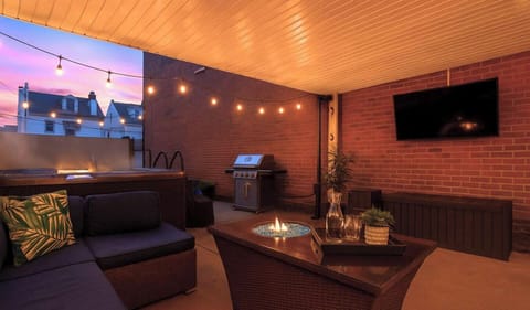 Relax in the cozy outdoor space with lounge seating, a grill, and a TV—perfect for evening gatherings.