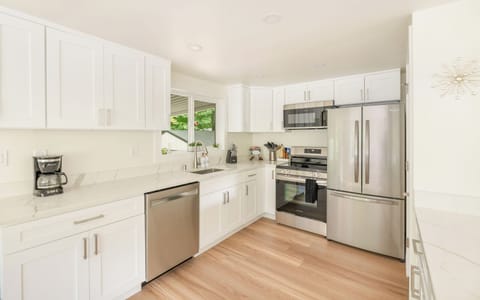 - Modern kitchen with stainless steel appliances  
- White cabinetry and stone counters for clean style  
- Fully equipped space for cooking and meal prep  
