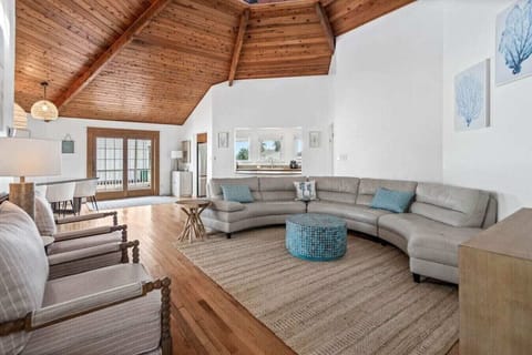 Unwind in this stunning open-concept living space where coastal charm meets rustic elegance beneath soaring wood-beamed ceilings.