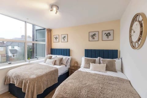 - Bright bedroom with two cozy double beds and soft bedding  
- Large window lets in natural light for a refreshing stay  
- Wall art and decor create a warm and welcoming atmosphere  