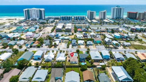 Aerial view shows a beachfront community with residential homes and high-rise condos along pristine turquoise waters and white sand beaches.