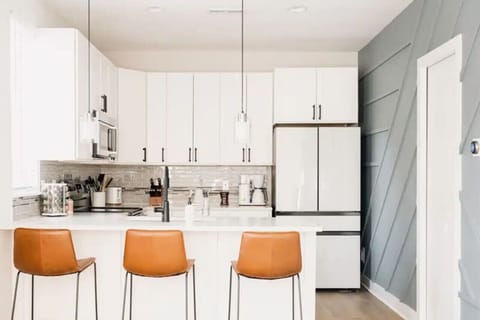 Bright modern kitchen with white cabinetry and leather counter stools