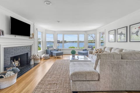 Cozy & spacious living room with a Smart TV, fireplace, and a breathtaking waterfront view.
