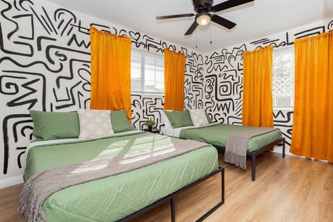Vibrant Double Guest Bedroom: Unwind in this playful and stylish guest bedroom featuring two double beds dressed in premium linens, bold graphic wall murals, bright blackout curtains, and warm hardwood-style flooring.