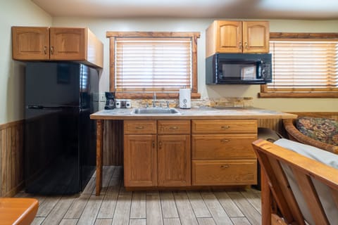 Kitchenette that includes a mini fridge, coffee maker, kitchen sink and microwave.