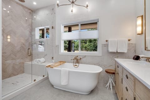 This luxurious primary bath has a soaking tub, white oak dual vanity, rain shower & toilet room. The ensuite exudes resort-like luxury.
