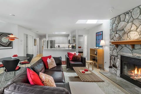 - Bright open living room with stone fireplace and natural light  
- Modern décor, red accents, and cozy seating perfect for relaxing  
- Steps to dining area and kitchen, creating an inviting social space  
