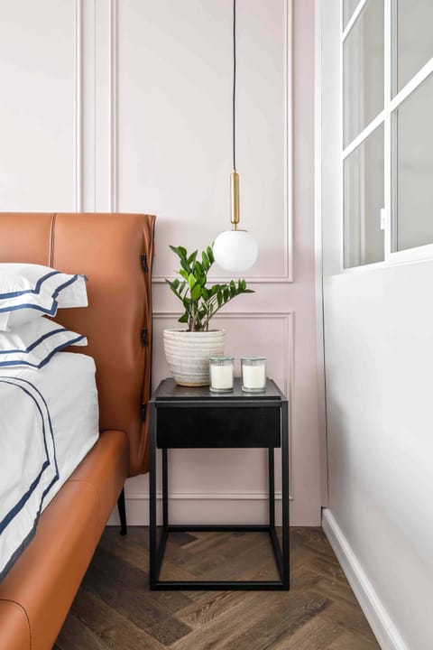 Stylish bedroom featuring a unique accent wall, contemporary lighting, and a high quality leather bed frame.
