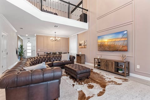 Relax in the spacious living area, where plush leather seating invites you to unwind. The warm tones of the cowhide rug complement the elegant decor, while large windows provide a welcoming glow, enhancing your comfort and style.