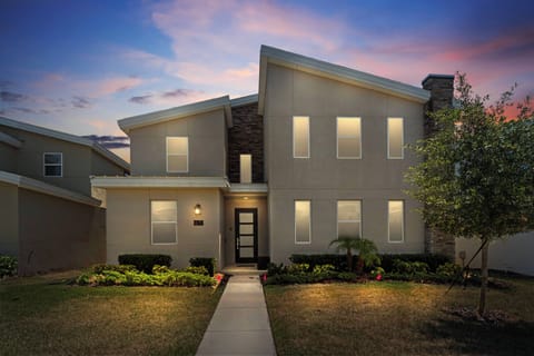 Discover the charm of this beautifully designed exterior with its sleek facade and large, welcoming windows. As dusk falls, the carefully landscaped yard adorned with vibrant flowers creates an inviting atmosphere for your visit.
