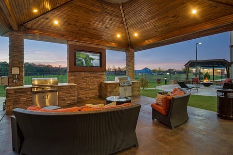 Gather around the outdoor seating under a beautiful wooden gazebo, perfect for BBQ evenings with friends.