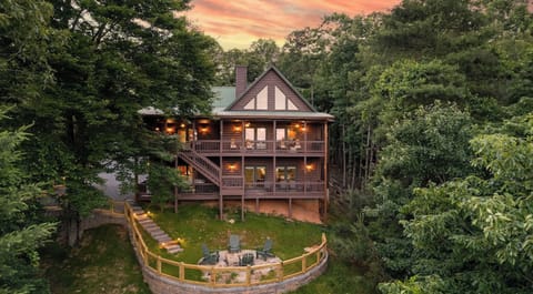 Wooded multi-story cabin with large windows, wooden siding, and wraparound deck.