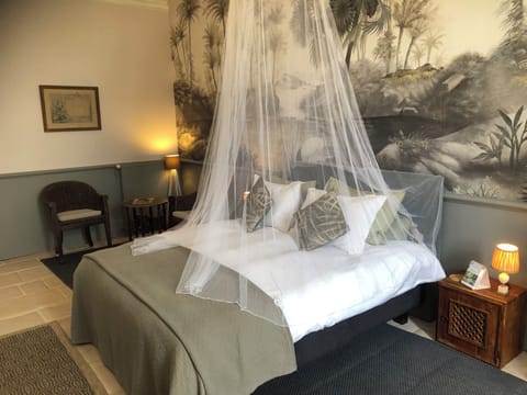 Comfortable king sized bed with mosquito net and side tables