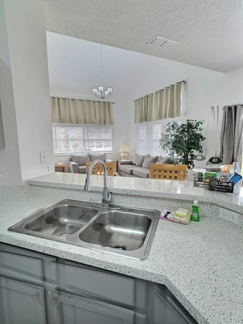 Enjoy the inviting warmth of this kitchen with sleek gray cabinets and a beautiful stone countertop, filled with natural light. The cozy living area features charming wood accents and comfortable furnishings, perfect for relaxing.