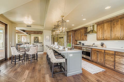 This chef-inspired kitchen boasts warm wood cabinetry, a large marble island with seating for four, and elegant lantern pendant lights. Perfect for hosting, the open layout is both stylish and functional.