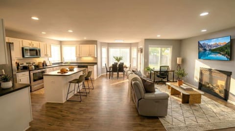 Open living, dining, and kitchen area with sofa seating, fireplace, TV, and breakfast bar.
