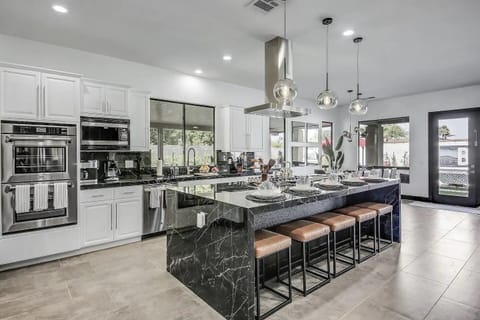 This gourmet kitchen features a bold black marble island with seating for six, top-of-the-line stainless steel appliances, and ample space to cook, dine, and entertain. Whether you're preparing a family meal or hosting a stylish dinner party, this open-concept design blends luxury and functionality seamlessly.