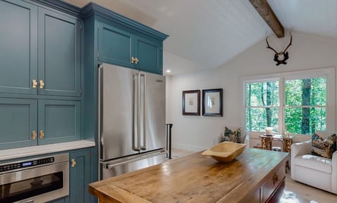 rustic kitchen with teal cabinetry and a large wooden island overlooking a forest view