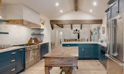 Modern kitchen with blue cabinetry, stainless steel appliances, and a rustic wooden island.