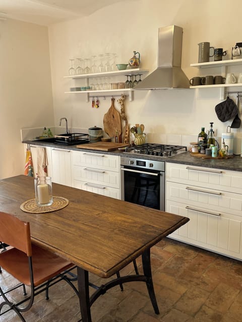 Antique farm table with hand-forged iron legs, a bench, and 4 leather chairs