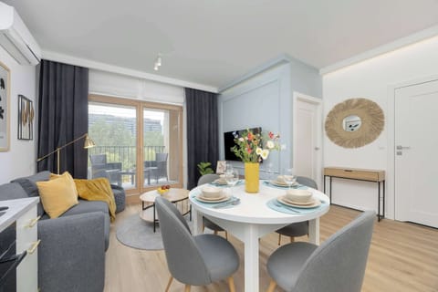 A stylish dining area with a round table, velvet chairs, and a bright open-concept layout connecting to the kitchen.