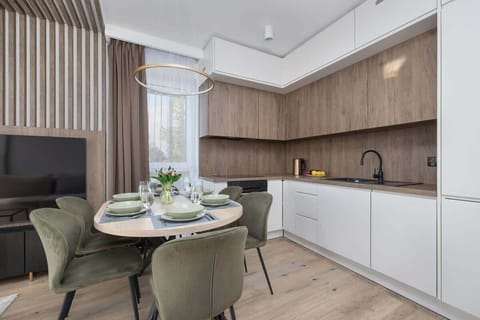 The kitchenette with dining area, featuring a table with chairs and light cabinets, provides a practical and pleasant space for shared meals.