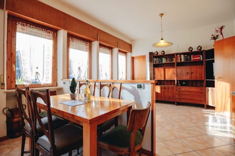 Spacious, bright dining room with wooden furnishings and large windows, perfect for sharing family meals in the apartment in Peschiera del Garda.