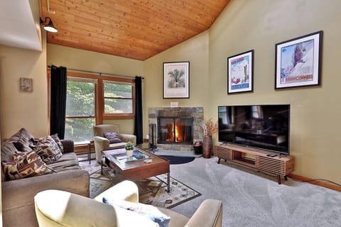 The living room of our charming Trail Creek condo at Killington Resort features a sleeper sofa, a smart TV, a wood-burning fireplace, and a small balcony to enjoy the mountain air.