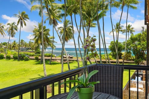 1st lanai with direct ocean views framed by towering palms — this is the first thing you see when you step outside at Prince Kuhio 2-7.