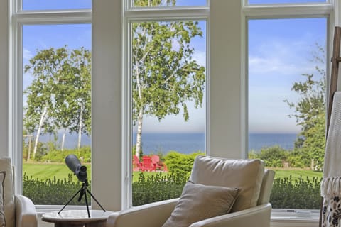 Open concept main level boasting floor to ceiling windows along the lakeside, luxury furniture and gas fire place.