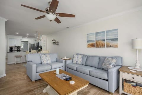 A bright and airy open-concept living room featuring comfortable light blue seating.