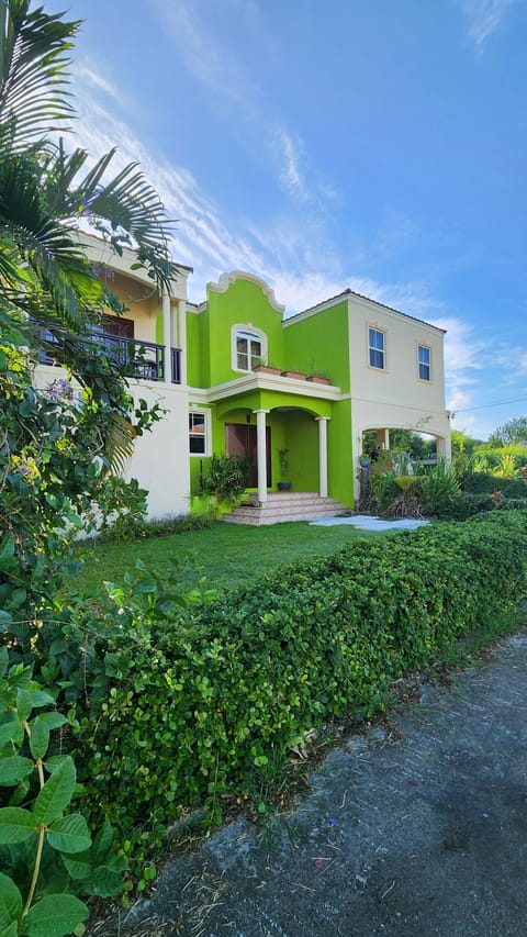 Stunning 2-story villa with vibrant green & beige exterior, tropical landscaping