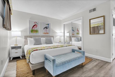 Relax in your beautifully appointed bedroom featuring a plush king bed, coastal bird artwork, and elegant blue bench seating - your perfect retreat after a day of adventures.