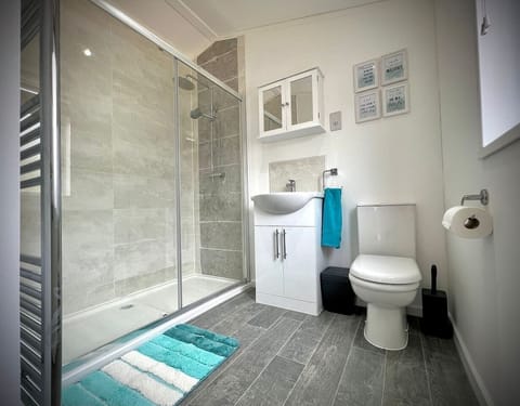 The spacious shower room features a toilet, a basin, and a luxurious waterfall shower. Soft bathmat, fresh hand towels and non slip shower mat are provided for your comfort.