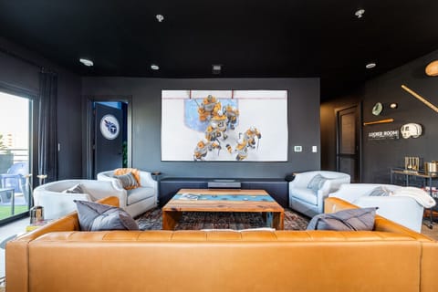 Living room with leather sofa, accent chairs, giant screen/projector  and games, open to the dining and kitchen area, offering plenty of seating