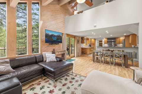 Open great room space with L-shaped couches, gas fireplace, TV, and dining for 8