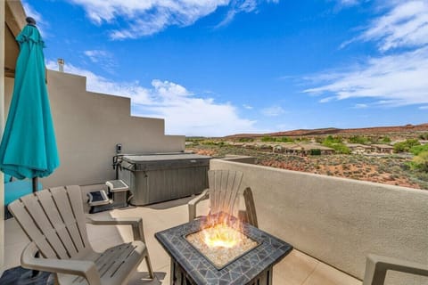 Private balcony at Washington Utah short-term rental featuring fire pit, seating area, and stunning desert views of red rock cliffs near St. George