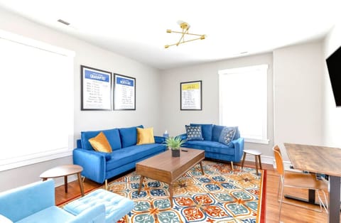Kick back in the Monopoly-inspired living room with two plush couches, a lounge chair with ottoman, and a dedicated workspace. Bright pops of modern décor set the scene, while the Roku TV keeps entertainment just a click away.