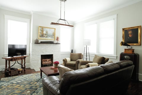 Large living room outfitted with a clean leather sofa and the most comfortable oversized chairs, oil paintings, and many interesting antiques to take you back in time.