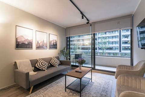 Relax in this stylish living room with a cozy sofa, chic decor, and a view of the cityscape from the spacious balcony.