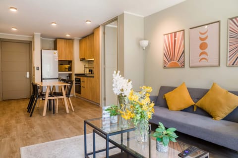 Private living room with a gray sofa, mustard cushions, and a connected dining area beside the warm wood kitchen.