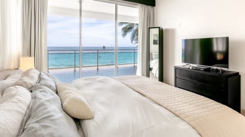 Master bedroom featuring stunning ocean views, large windows, air conditioning, and a peaceful beachfront atmosphere designed for rest, comfort, and total relaxation.